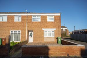 a brick building with a white door and a trash can at Pine House By Horizon Stays in Hartlepool