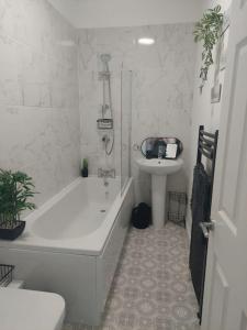 a white bathroom with a tub and a sink at Cosy home in Barnsley centre in Barnsley
