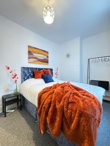 a bedroom with a bed with an orange blanket on it at Cosy home in Barnsley centre in Barnsley