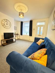 a living room with a blue couch and a clock at Cosy home in Barnsley centre in Barnsley