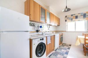 a kitchen with a washing machine and a refrigerator at Fantástico T2 AC Wi-FI e TV Cabo 2WC Toalhas e Lençóis in Altura