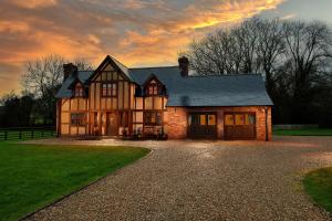 a large brick house with a sunset in the background at Finest Retreats - Ty Nant in Aberhafesp