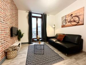 una sala de estar con un sofá de cuero negro y una bicicleta en la pared en LES 3 RIVIÈRES - Vue Imprenable & Hyper Centre, en Mont-de-Marsan