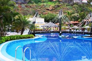 uma grande piscina com uma ponte sobre ela com uma montanha em Bahia Principe Sunlight San Felipe em Puerto de la Cruz