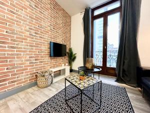 sala de estar con pared de ladrillo y TV en LES 3 RIVIÈRES - Vue Imprenable & Hyper Centre, en Mont-de-Marsan