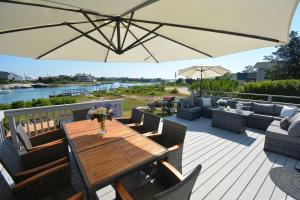 a wooden table and chairs on a deck with an umbrella at Sunset Beach House with 30ft Boat Dock in Shinnecock Southampton NY in Southampton