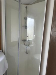 a white bathroom with a shower and a sink at Powys 37 in Borth