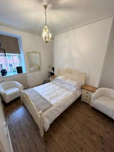 a bedroom with a white bed and a chandelier at Parade School Guest Rooms in Berwick-Upon-Tweed