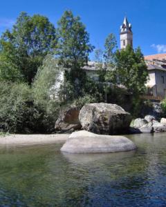 a rock in the water with a building in the background at Gîte du petit Taïchou in Luzenac