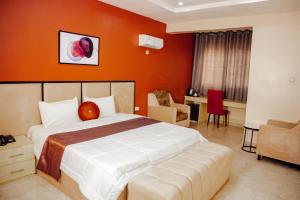 um quarto com uma cama grande e uma parede laranja em Nexus Xpress Hotel em Abuja