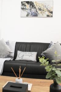 a black couch sitting in a living room at Cosy house in West Yorkshire in Batley