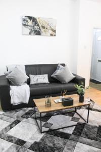 a living room with a black couch and a coffee table at Cosy house in West Yorkshire in Batley
