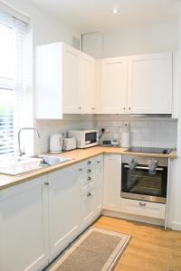 una cocina blanca con armarios blancos y fregadero en Cosy house in West Yorkshire, en Batley