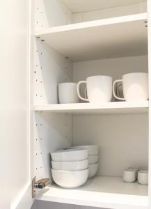 a shelf with white cups and bowls on it at Cosy house in West Yorkshire in Batley