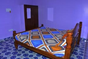 um quarto com uma cama de madeira e uma colcha colorida em Re leaf Resort em Auroville