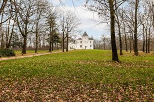 una casa blanca en una colina con árboles y césped en WijnKasteel Haksberg, en Tielt