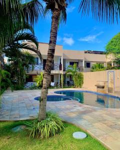 a resort with a palm tree and a swimming pool at Flat Barra do Cunhaú in Canguaretama