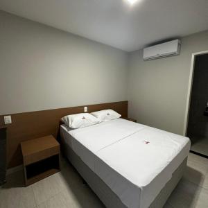 um quarto com uma cama branca e ar condicionado em ONIX AGUAS CLARAS em Salvador
