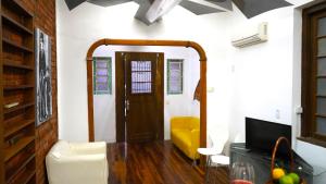 ein Wohnzimmer mit einem gelben Sofa und einem TV in der Unterkunft Casa antiga, linda ótima localização prox ao shopping in Porto Alegre