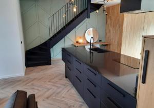 une cuisine avec un comptoir noir et un escalier dans l'établissement Bramendijk, à Groede