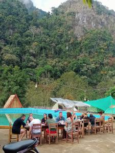 a group of people sitting at tables near a pool at NongKhiaw CampingSite Swimming Pool in Ban Nongkham