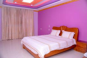 a bedroom with a large bed with purple walls at lake palace beach hotel in Bujumbura