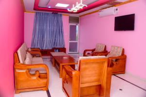 Habitación con paredes rosas, mesa y sillas. en lake palace beach hotel, en Buyumbura