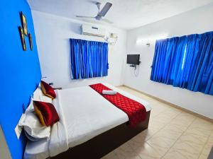 Schlafzimmer mit einem Bett mit einer roten Decke und blauen Vorhängen in der Unterkunft SEA WALK Serenity beachside in Puducherry