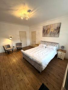 a bedroom with a large bed and a chandelier at Parade School Guest Rooms in Berwick-Upon-Tweed