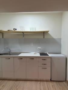 - une cuisine avec des placards blancs, un évier et une étagère dans l'établissement White apartment, in the center of Tirana, à Tirana