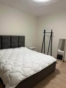 - un lit blanc dans une chambre blanche avec un miroir dans l'établissement White apartment, in the center of Tirana, à Tirana