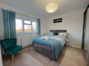 a bedroom with a bed and a green chair at New Stylish 2-Bed Retreat in Central Windsor in Windsor