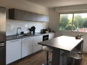 a kitchen with white cabinets and a table and a window at T3 Anglet, entre Biarritz et Bayonne in Anglet