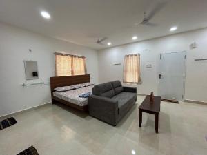 a bedroom with a bed and a couch and a chair at SAIBALA HOMESTAY - AC 1 BHK STUDIO NEAR AlRPORT in Chennai