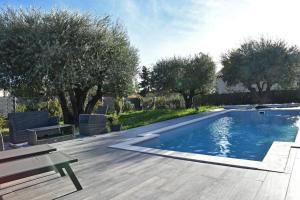 una piscina con un banco y algunos árboles en Villa Le Clos des Oliviers en LʼEscale