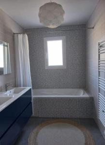 a bathroom with a tub and a sink and a window at Villa Le Clos des Oliviers in LʼEscale