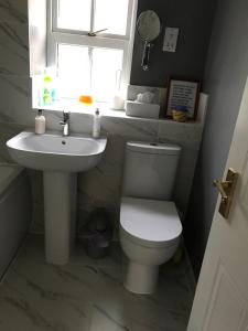 a bathroom with a toilet and a sink and a window at 18 Wixon Path in Buckinghamshire