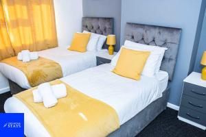 duas camas num quarto com amarelo e branco em 2ndHomeStays -Walsall- Charming 3-Bedroom House em Walsall