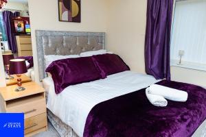 a bedroom with a large bed with purple sheets at 2ndHomeStays-West Bromwich- 2-Bedroom Maisonette in West Bromwich