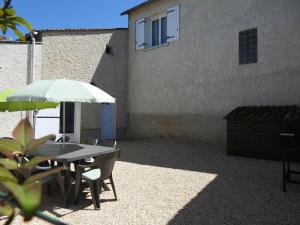 a table and chairs with an umbrella and a building at "Peace & love house" en campagne de Poitiers in Montamisé