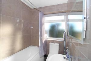 uma casa de banho com um WC, uma banheira e uma janela. em Stunning 2 bedroom in Luton ! em Luton