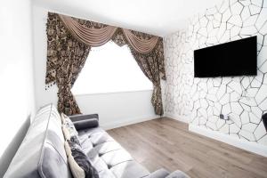 uma sala de estar com um sofá e uma televisão na parede em Stunning 2 bedroom in Luton ! em Luton