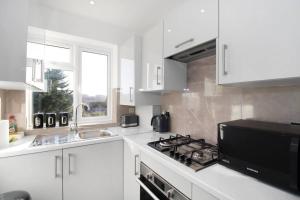 a white kitchen with a stove and a sink at Stunning 2 bedroom in Luton ! in Luton