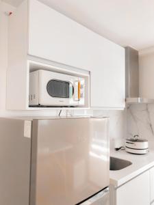 uma cozinha branca com um micro-ondas em cima de um frigorífico em JD Serviced Suite at Azure North Pampanga em San Fernando