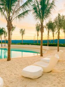 - un fauteuil blanc sur la plage avec des palmiers dans l'établissement JD Serviced Suite at Azure North Pampanga, à San Fernando