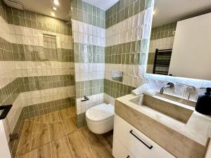 a bathroom with a toilet and a sink and a mirror at Moderno y acogedor apartamento con terraza “ Llebeig” in Sóller