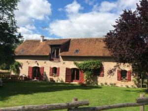 ein großes Haus mit roten Türen und einem grünen Hof in der Unterkunft Propriété en Sologne avec étangs in Villemurlin