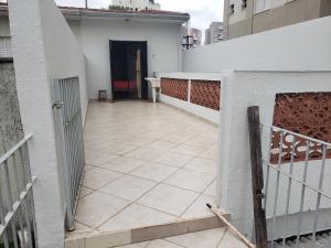 a balcony with a white wall and a gate at Metro pra da árvore in São Paulo