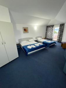 two beds in a room with blue carpet at Sea View Rooms Briz in Nesebar