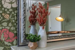 two white vases sitting on a table in front of a mirror at Rest & Recharge at Mapledon House (15mins to City Centre) in Manchester